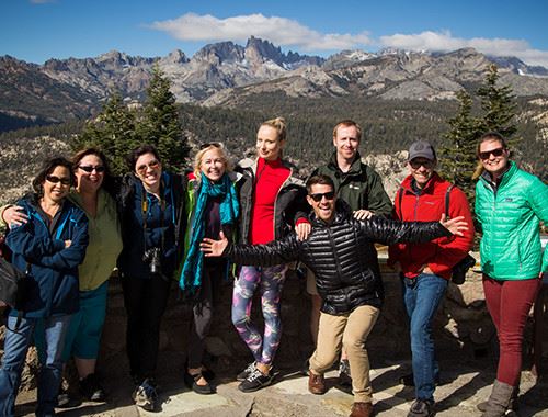 A group of people posing for a picture with a mountain range in the background